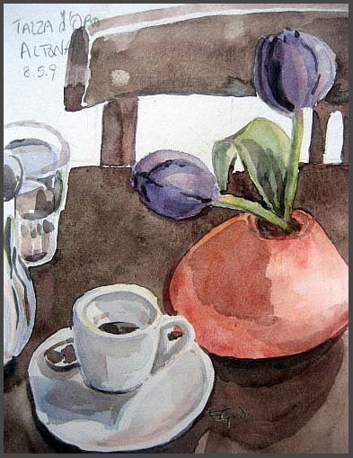 Two purple tulips in an orange vase next to a coffee cup on a cafe table